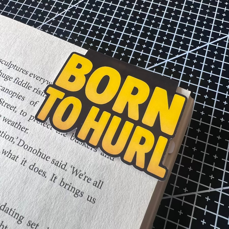 Sticker with 'Born to Hurl' text on a book page with a grid background
