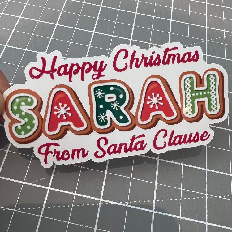 Sticker with 'Happy Christmas Sarah From Santa Clause' text on a grid background