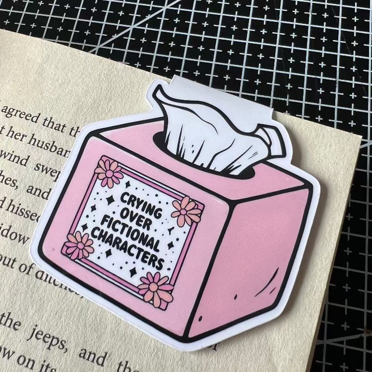 bookmark of a pink tissue box with text 'Crying over fictional characters' on a textured surface.