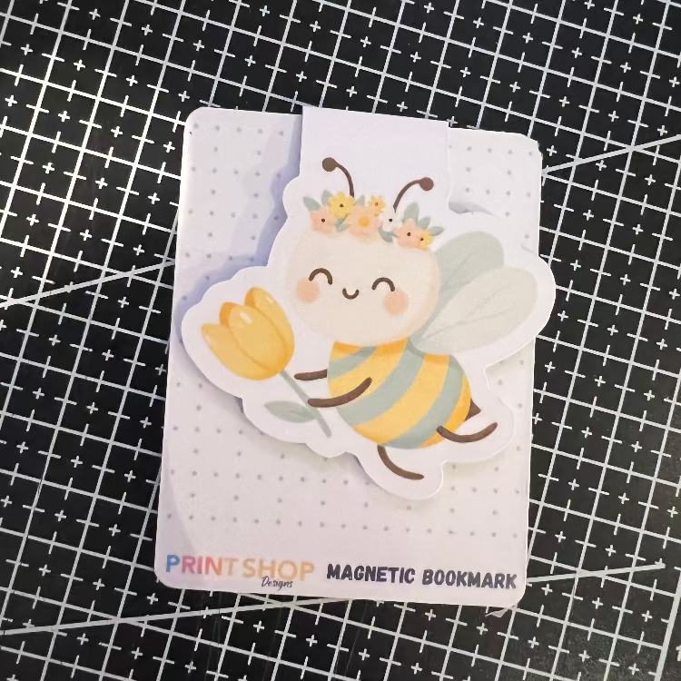 Magnetic bookmark with a bee design on a black grid background