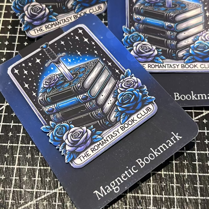 Magnetic bookmark with book and rose design on a textured surface