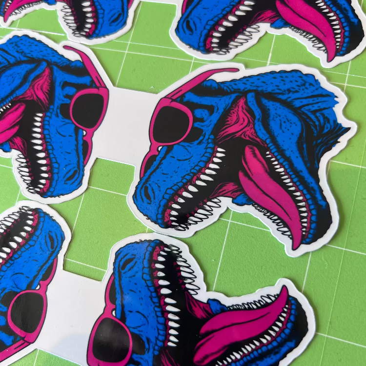 Stickers of a blue and pink creature head on a green grid background