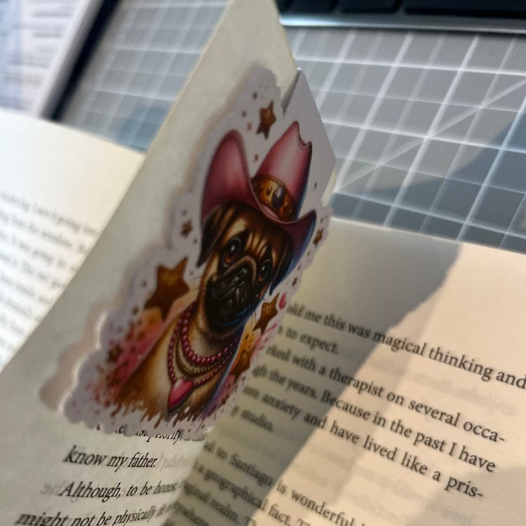 Book with a sticker of a dog wearing a cowboy hat on a cutting mat.