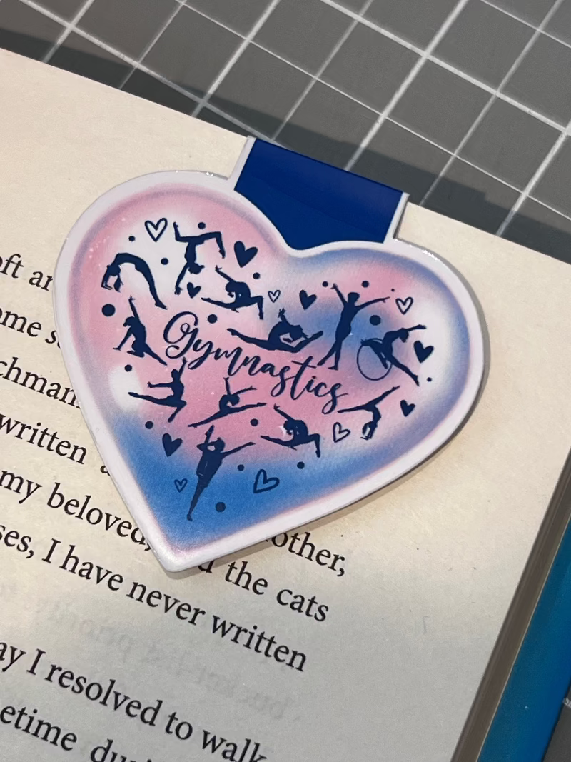 Heart-shaped gymnastics-themed bookmark on a book page