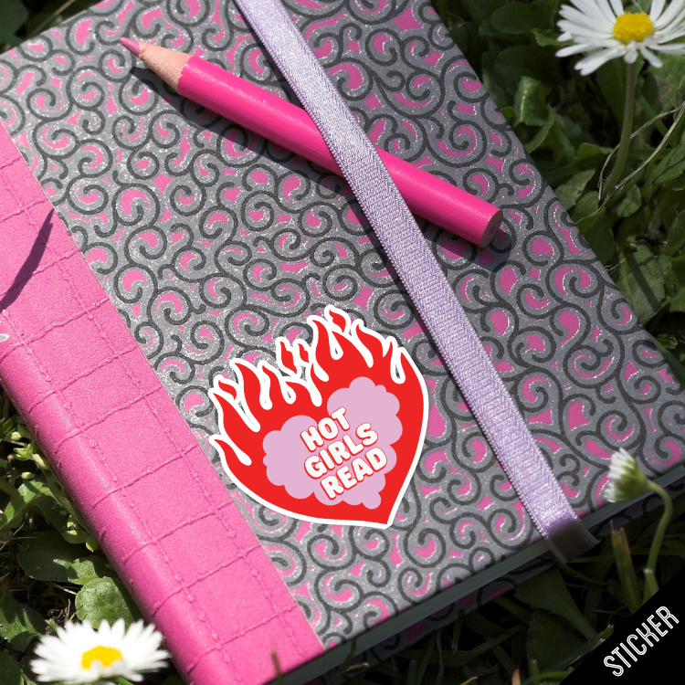 Pink notebook with a purple pen and 'Hot Girls Read' sticker on a grassy background