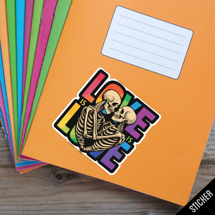 Sticker with skeletons and rainbow text on an orange notebook with colorful pages.