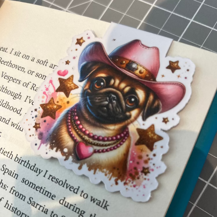 Sticker of a pug dog wearing a pink cowboy hat on a book page.