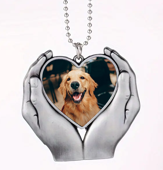 Heart-shaped pendant with a photo of a golden retriever held in hands on a white background