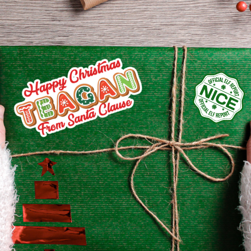 Green gift box with 'Happy Christmas Teagan from Santa Clause' text and 'Nice' stamp on a wooden surface.