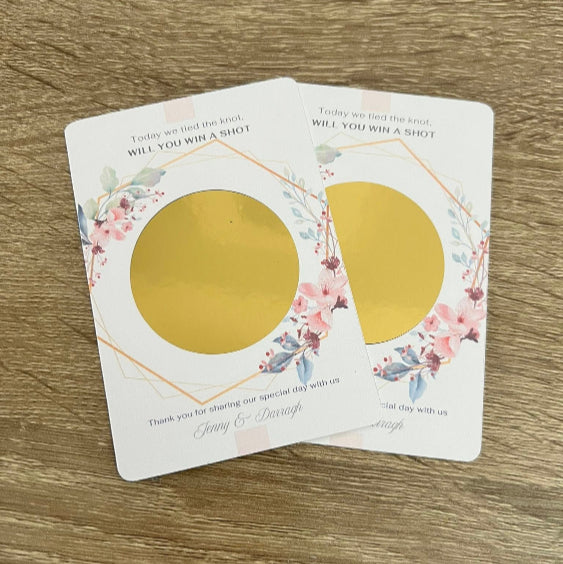 Two gold circular objects on a decorative card with floral designs on a wooden surface